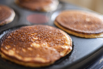 Golden brown homemade pancakes cooking on griddle, close-up of breakfast preparation