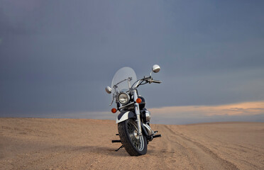 Off-road motorcycle standing still in the open desert beneath heavy clouds. A strong visual of freedom, rugged adventure, and the thrill of riding through wild, untamed terrain.