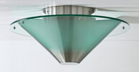 Fototapeta premium Ceiling fixture, modern design. Metal base supports frosted glass cone. Clean lines, simple aesthetic, mounted flush to ceiling.