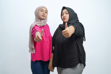 Cheerful Asian Indonesian Muslim Women Giving Thumbs Up Gesture in Studio Portrait