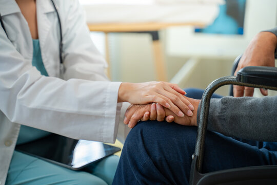 Doctor Comforts Smiling Elderly Man in Wheelchair During Clinic Visit,Arthritis hand,gout knee pain,geriatric doctor consulting examining comforting elderly senior age in medical clinic or hospital