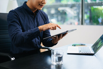 man multitasking with smartphone and laptop in bright modern office. Ideal for business, remote...