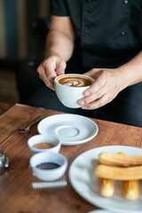 Holding a cup of coffee while sitting near a table