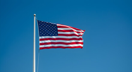 Fototapeta premium American Flag Waving Against Blue Sky | Patriotic Symbol of Freedom, Democracy and Independence for National Holidays and Government Marketing