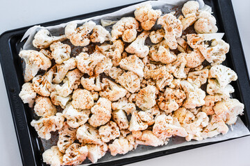chopped cauliflower with spices on baking tray ready for roasting