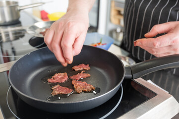 The chef fries veal in a frying pan. 
