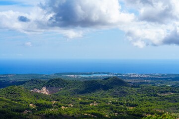 Obraz premium Experience the serene beauty of Mallorca, Spain. Lush green hills meet the azure sea under a cloudy sky, creating an idyllic landscape perfect for nature lovers and travelers.