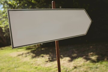 Fototapeta premium Front view of blank direction sign pointing to the right against forest