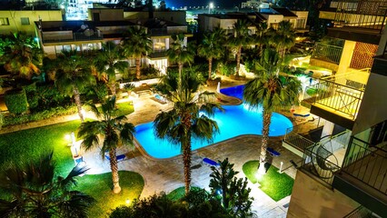 Experience the charm of a tropical night with a beautifully illuminated resort pool surrounded by...