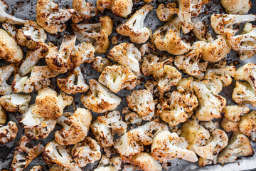 chopped cauliflower with spices on baking tray ready after roasting