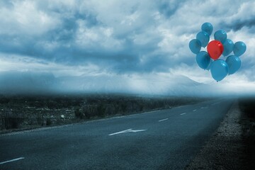 Cluster of blue and red balloons is floating over paved road, flat design under overcast sky
