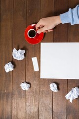 Man holding coffee cup by crumpled paper