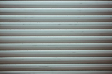 Closed metal roller shutter door is showing muted greenish-gray horizontal slats in flat design