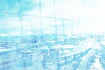 Defocussed image of modern cityscape and blue sky reflected in glass building front, with copy space