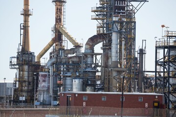 Flat design refinery unit depicting tall distillation towers with pipelines and red-brick building