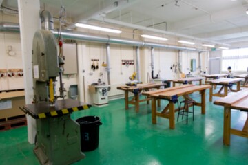 Stationary band saw is standing in flat design workshop showing benches, miter saws, dust ducts