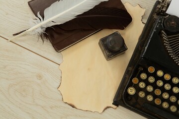 Typewriter, feathers and stamp on table