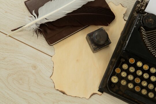 Typewriter, feathers and stamp on table