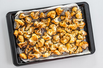 chopped cauliflower with spices on baking tray ready after roasting