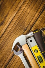 showing flat design hammer, wrench, spirit level, screwdriver, tape measure resting on wooden plank