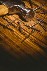 Flat design steel claw hammer is resting on wooden workbench with scattered steel nails