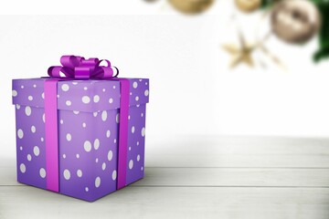 Flat design purple polka-dot gift box is sitting on tabletop with magenta bow, starfish and foliage