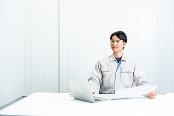 パソコンの前に座る作業着を着た男性