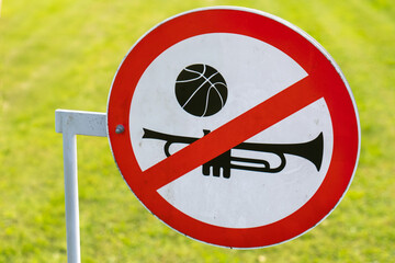 Round prohibition sign with a trumpet and basketball symbol, indicating no music or ball games...