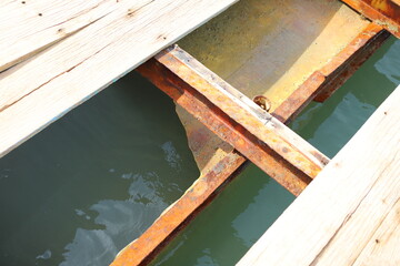 Rusted metal beams on a damaged floating platform offshore, structural parts partially hidden...