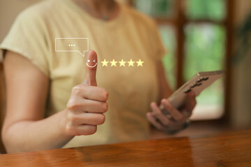 Asia woman using smartphone for select smiley face icon for client evaluation and customer satisfaction after use product and service concept...