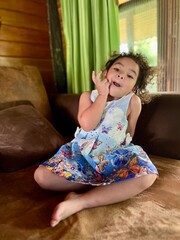 Little girl in a blue dress sitting on the sofa