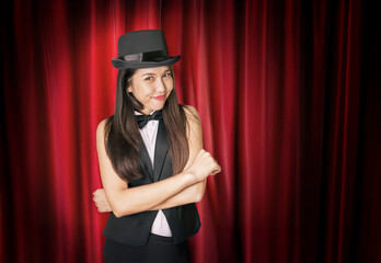 Asian magician standing poised on a crimson draped stage, ready to mesmerize her audience with an...