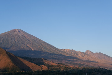 Breathtaking morning panorama of Mount Rinjani from Bukit Selong, Sembalun—sunlight softly...