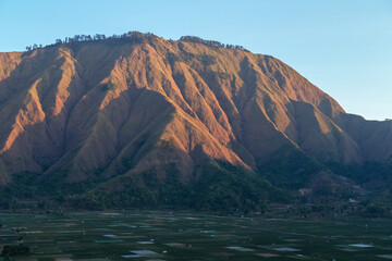 Majestic view of Pergasingan Hill glowing under soft morning light, seen from Selong Hill in Sembalun, Lombok—where dramatic ridgelines meet tranquil rural charm.