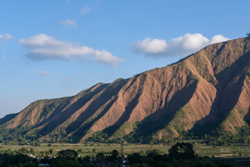 Majestic view of Pergasingan Hill glowing under soft morning light, seen from Selong Hill in Sembalun, Lombok—where dramatic ridgelines meet tranquil rural charm.