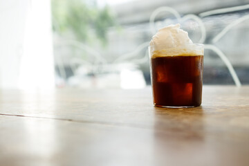 Cup of creation black coffee drink and coconut ice cream on rustic wooden table by the window.