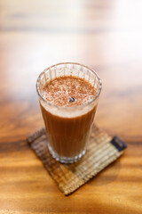 Cup of delicious iced chocolate on wooden table background by the window.