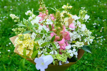 Wrapped flower bouquet made of mixed spring flowers. Beautiful pastel colored fresh flowers arrangement. Birthday bouquet with snapdragons and matthiola stock.