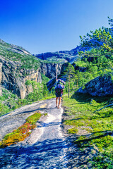 Naklejka premium Man hiking with a big backpack uphill in a mountain landscape a sunny summer day