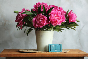 Pink peonies in a metal bucket and july 21st on wooden perpetual calendar