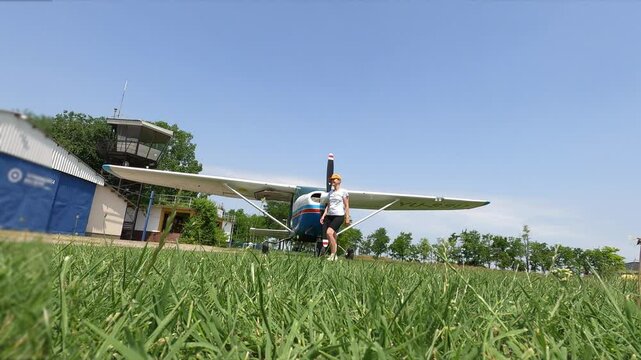 An athletic looking woman walks away from a small plane - a Cessna 182