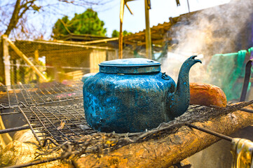 Object Series : Old kettle on charcoal stove. A worn aluminum kettle sits on a metal grate. A kettle that has been used for a long time in the countryside.