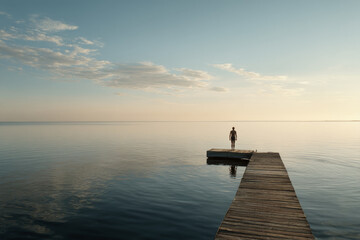 A man dives from a wooden pier into the sea.