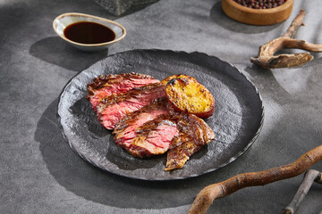 Bavette steak with grilled potato, bright lighting, overhead composition