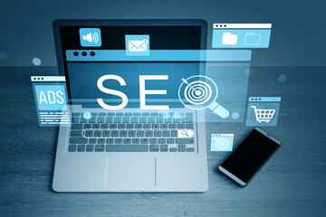 SEO and marketing strategy icons hovering over laptop and smartphone on desktop surface in digital...