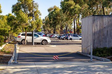 Entrance of an Australian suburban public car park is cordoned off with a chain barrier and a...