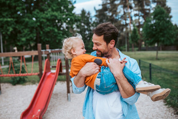 Father playing with toddler son outdoors in park