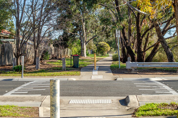 A suburban pedestrian crossing features a speed bump on the road to slow down vehicles, enhancing safety for pedestrians and cyclists, allowing for safe access to the street in Melbourne, Australia.