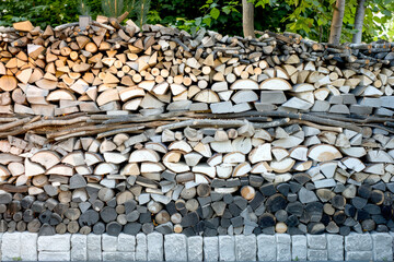 Neatly Stacked Logs and Stones in Natural Outdoor Setting Displaying a Textured and Organized Woodpile Pattern for Rustic and Natural Aesthetic