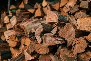 Close-up of stacked chopped firewood with visible texture, bark, and natural grain patterns in warm tones
